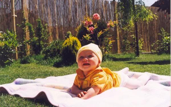 baby laying on picnic blanket grass with hat on